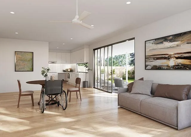 A bright, open-plan accessible home with a wheelchair at the dining table